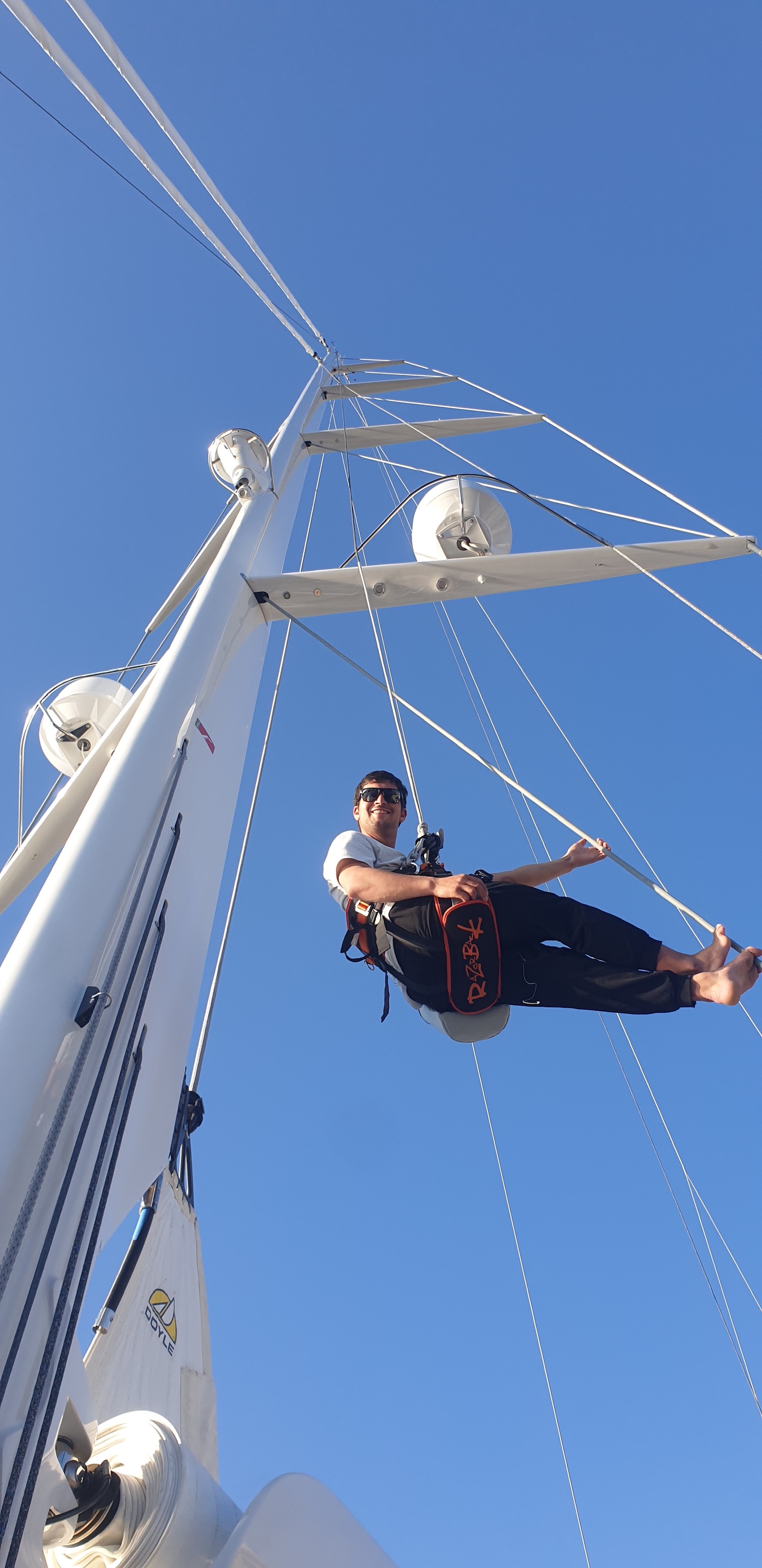 Adrián suspendido mientras inspecciona la jarcia de un velero